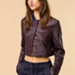 Mujer de tez clara y cabello marron vistiendo una chaqueta elegante color brown con dos botones frontales en la parte superior y cuello color navy.  Estilo otoño invierno conbinado con jeans oscuros.