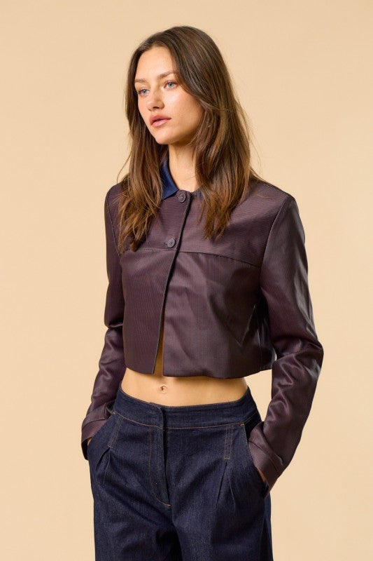Mujer de tez clara y cabello marron vistiendo una chaqueta elegante color brown con dos botones frontales en la parte superior y cuello color navy.  Estilo otoño invierno conbinado con jeans oscuros.