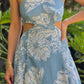 Vestido maxi azul con estampado floral blanco, escote halter y detalles cutout. Diseño elegante ideal para verano o vacaciones