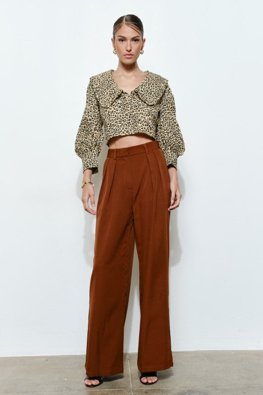 Foto de una mujer luciendo un pantalón de cintura alta con presillas para cinturón estiliza la figura y ofrece múltiples opciones para crear looks versátiles.&nbsp; Aporta volumen y una caída impecable, mientras que su silueta wide leg proyecta elegancia y alarga visualmente las piernas. Color Bronce o Terracota.  Lo consigues en la mejor boutique de Puerto Rico, Enso Amara.