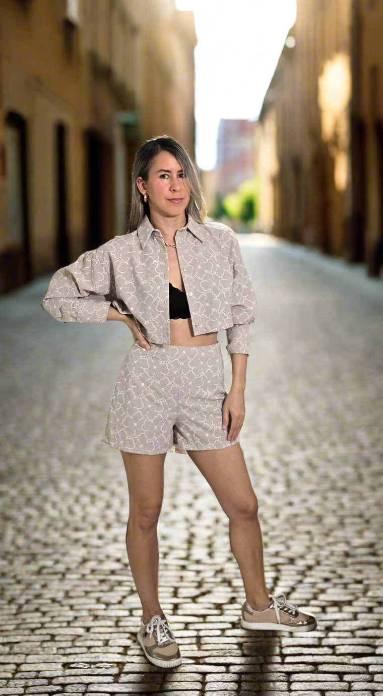 Mujer rubia con un set de camisa manga larga y botones frontales y un pantalon corto con diseño en color crema claro.
