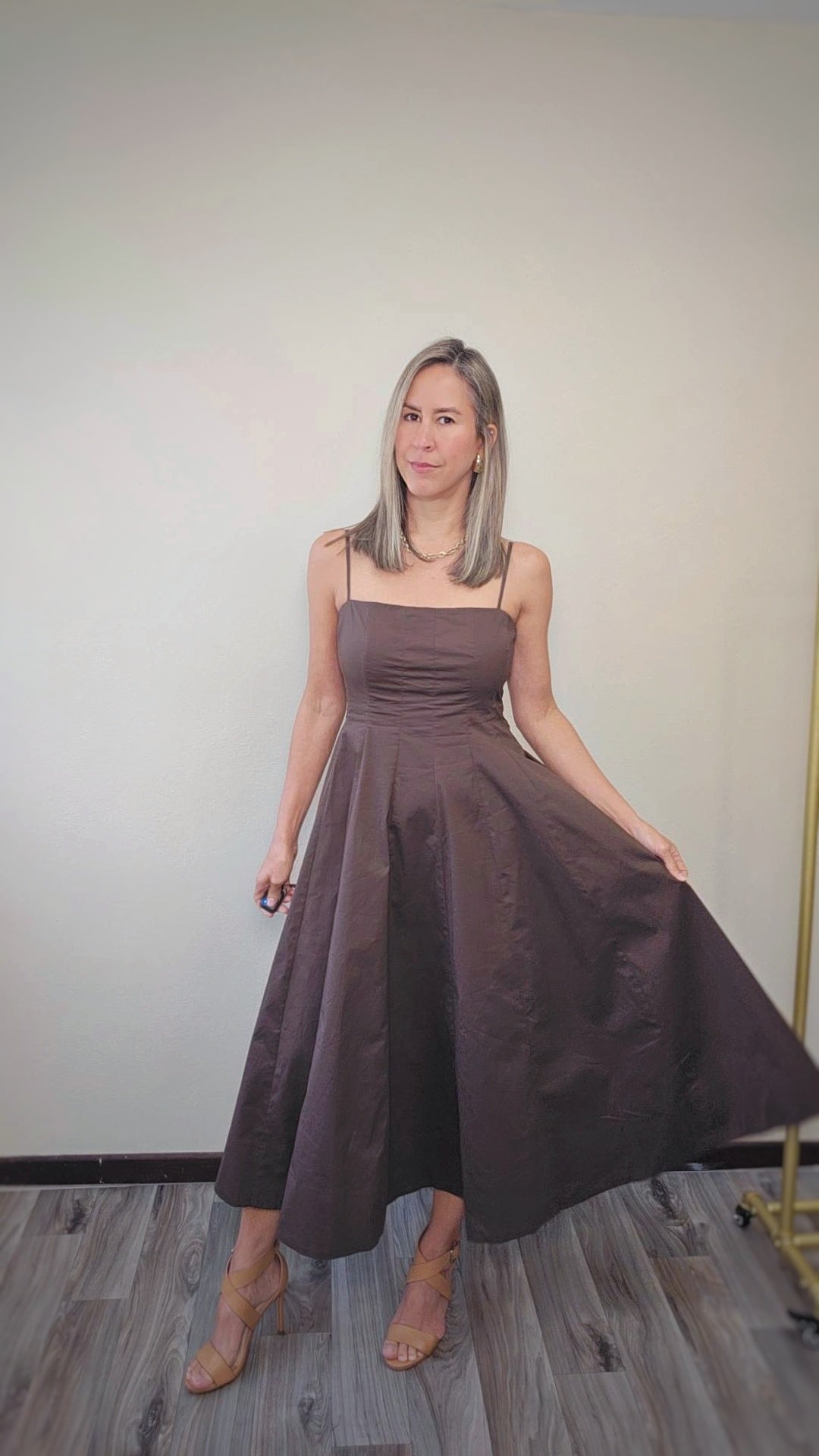 Imagen de mujer luciendo un vestido largo color brown.  Con manguillos tipo espagueti y diseño que afina la cintura con una amplia falda que da movimiento.
