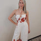 Jumpsuit con top strapless estilo halter y tira cruzada en la parte delantera, espalda abierta con elásticos y corte relajado, incluye bolsillos y cierre de zipper trasero."