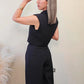 Imagen de espalda de mujer con cabello color rubio visitiendo un set de vest sin manga con botones frontales y pantalon a juego en color negro frente a un fondo neutro.  Este set es una pieza premium de la coleccion de new arrivals de la boutique Enso Amara.