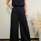 Imagen de cuerpo de mujer visitiendo un set de vest con cuello en v, sin manga con tres botones frontales y pantalon  estructurado a juego en color negro frente a un fondo neutro.  Este set es una pieza premium de la coleccion de new arrivals de la boutique Enso Amara.