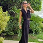 Imagen de mujer con cabello color rubio visitiendo un set de vest sin manga con botones frontales y pantalon a juego frente a un jardin llamativo con colores verdes.  Utilizando unas gafas para el sol color negras.  Este set es una pieza premium de la coleccion de new arrivals de la boutique Enso Amara.