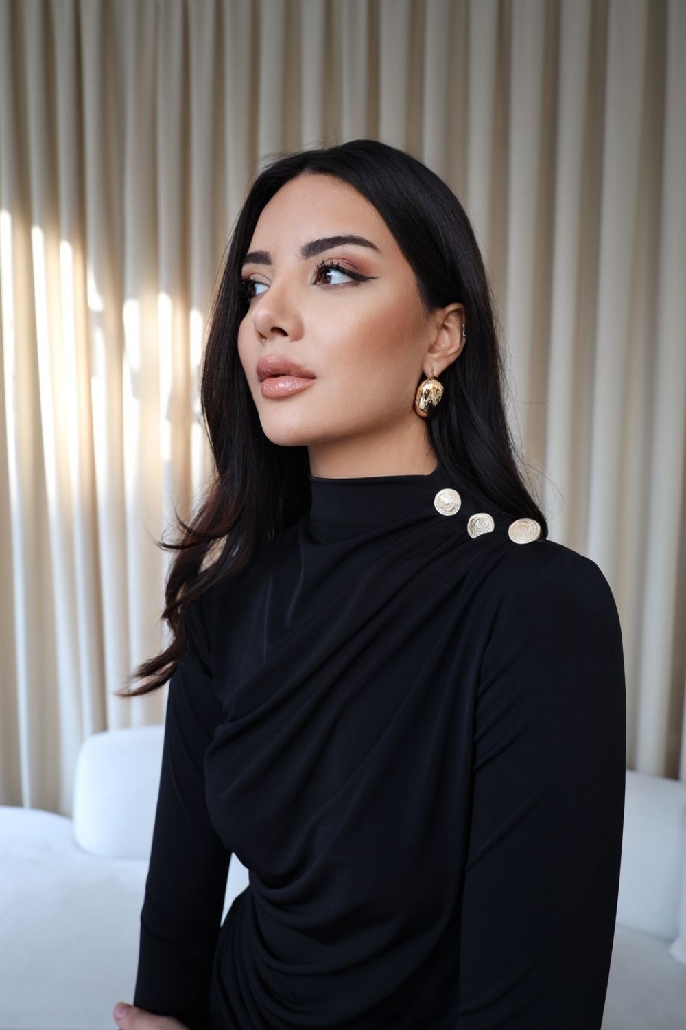 Top negro de manga larga con diseño audaz y drapeado frontal; incluye botones dorados y cierre trasero, perfecto para cualquier ocasión, desde la oficina hasta cenas elegantes