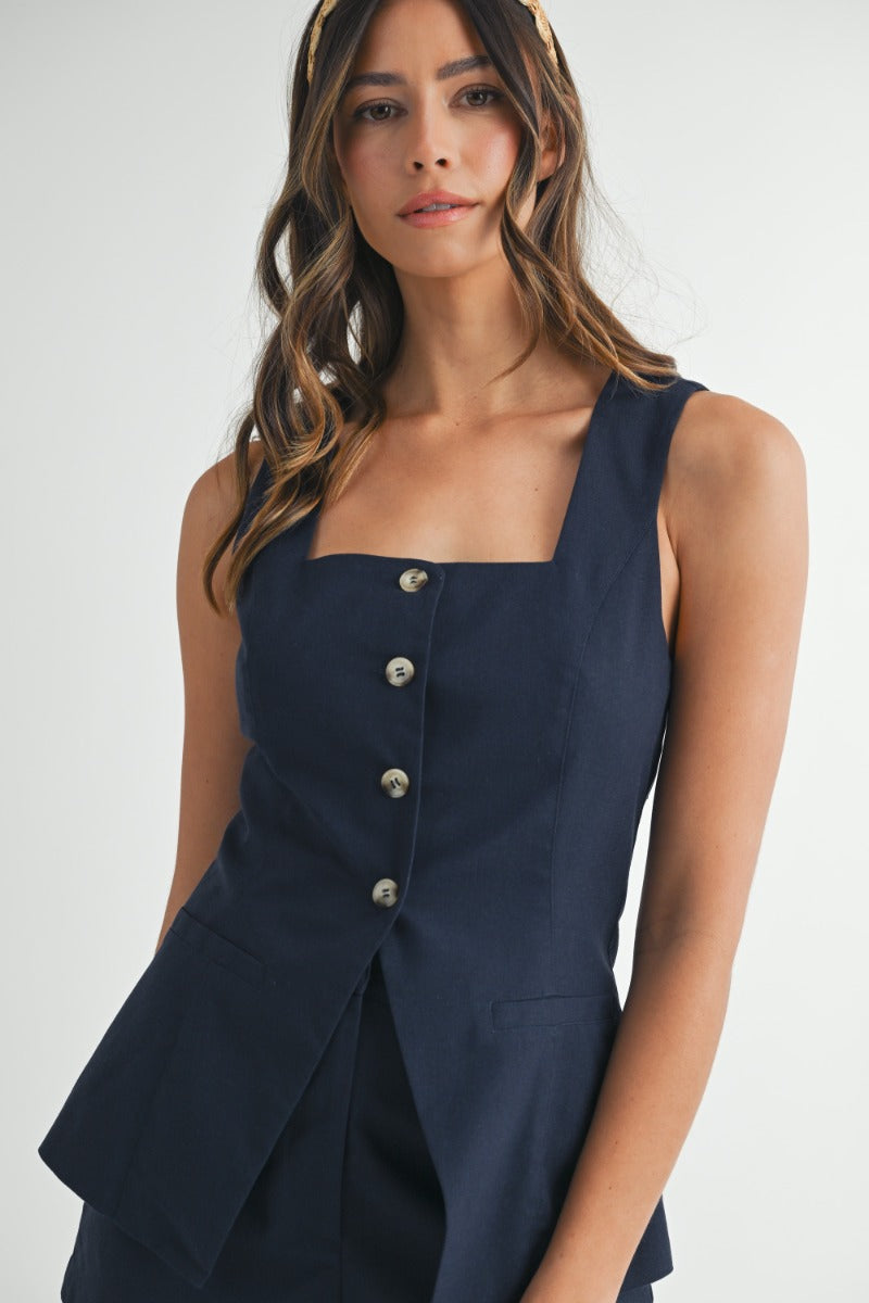 Mujer con cabello rubio viste un set de vest con cuello cuadrado y pantalon corto en color navy blue.