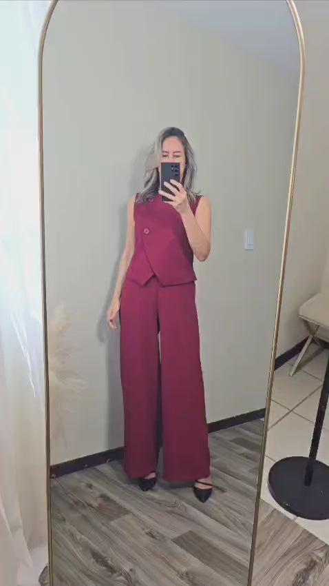 Video que muestra una mujer rubia tomandose un video frente al espejo.  Viste un conjunto de vest y pantalon color burgundy perfecto para ir a trabajar, una reunion formal, seminario. 